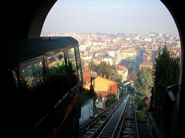 Funicular car descending steep tracks toward the misty city below