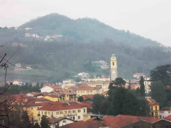 Yellow bell tower above red rooftops, misty hill in the background
