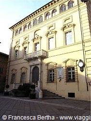 Renaissance stone facade with arched windows and balcony in sunny daylight