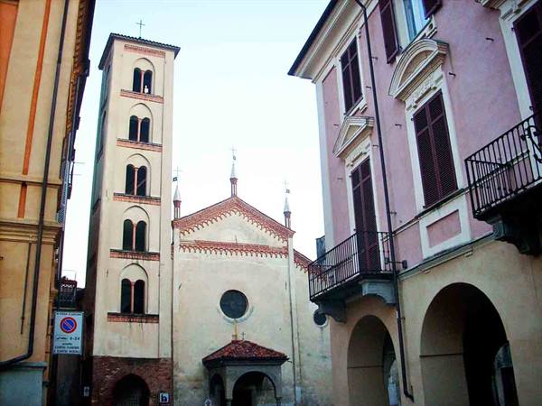 Romanesque bell tower and church facade among arcaded buildings, morning light