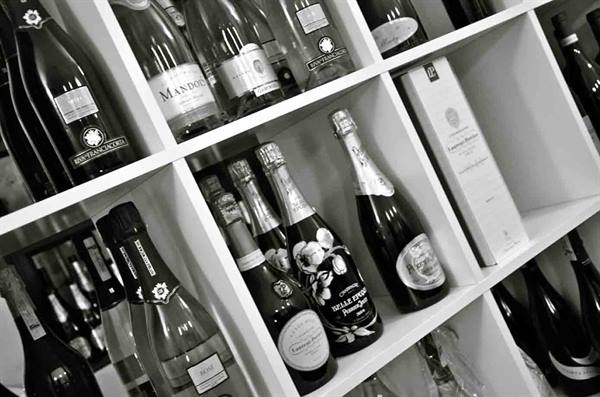 Champagne and sparkling wine bottles in black and white on white shelves
