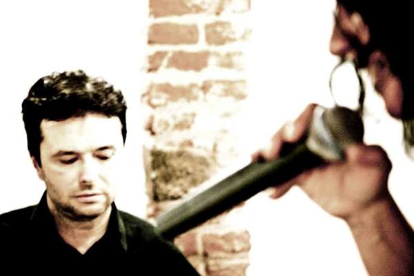 man in black with eyes closed beside a hand holding a microphone