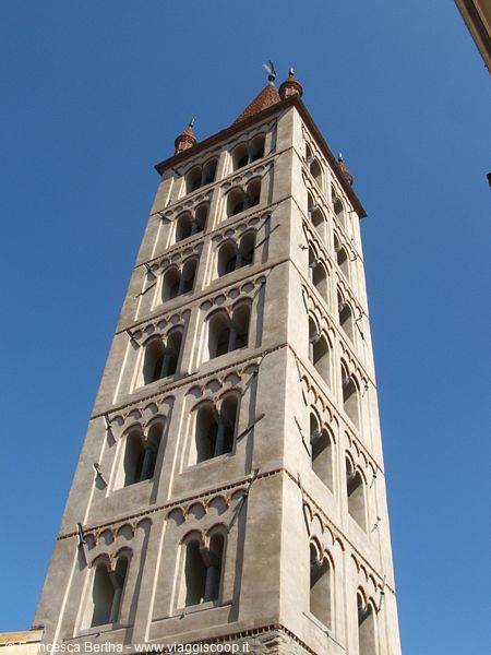 Romanesque stone bell tower with arched windows against blue sky
