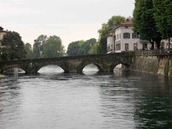 Old stone arch bridge over the river, houses overlooking the water