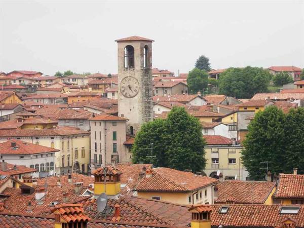 clock bell tower rising above red-tiled rooftops in an Italian town