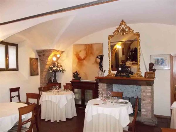 Restaurant dining room with white vaults, stone fireplace, gilded mirror and set tables