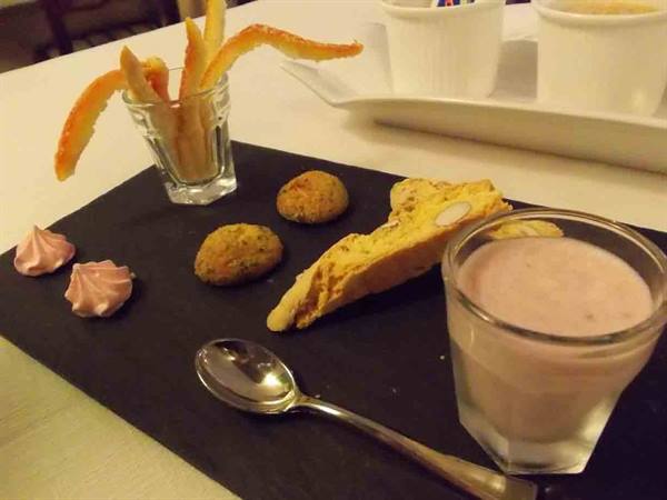 Desserts on black slate: cantuccio, cookies, meringues and pink cream in glass