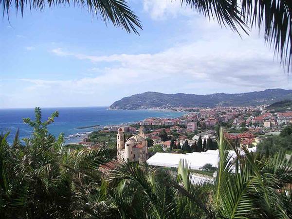 Church bell tower among palms above the coastal town and blue Ligurian sea