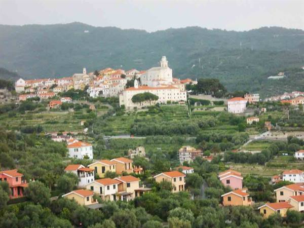 Hilltop village with colorful houses and white church among olive groves