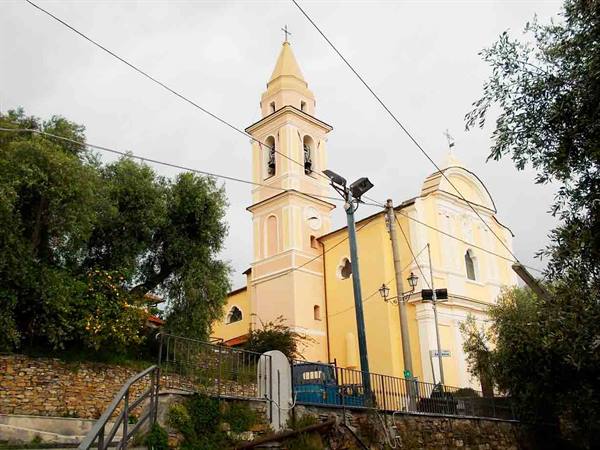 Yellow church with bell tower among trees and power lines, gray sky