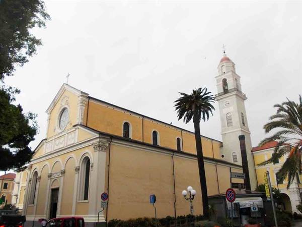 Yellow church with white bell tower and palm trees under grey sky