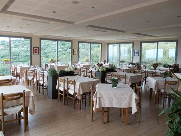 Restaurant dining room with set tables and windows over green hills