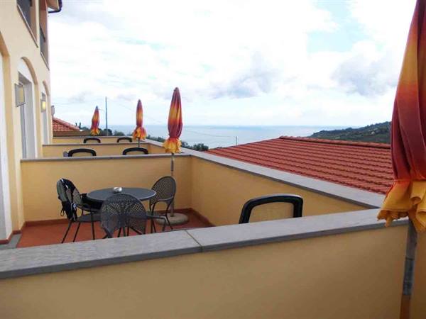 Terrace with metal tables and folded umbrellas overlooking the sea