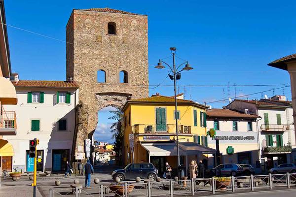 Medieval stone tower with arch rising over colorful houses in town square