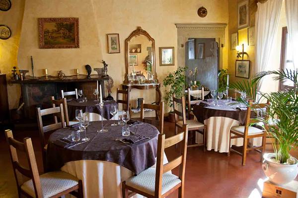 Restaurant dining room with set tables, dark tablecloths, fireplace, antique mirror and natural light