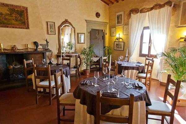 Rustic restaurant dining room with set tables, fireplace, antique mirrors and window light