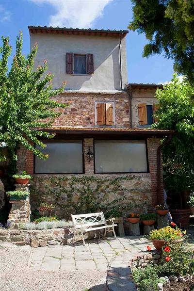 Stone farmhouse with wooden shutters and white bench in the courtyard