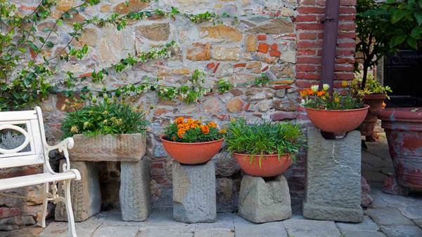 Flower pots on stone stumps against rustic brick wall