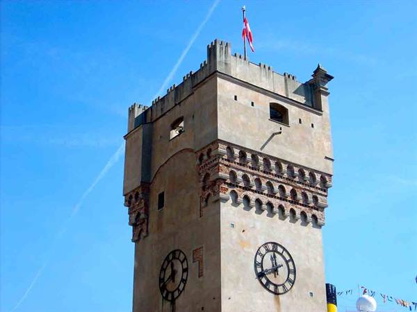 Torre Apponale in Riva del Garda, stone clock tower with flag against blue sky