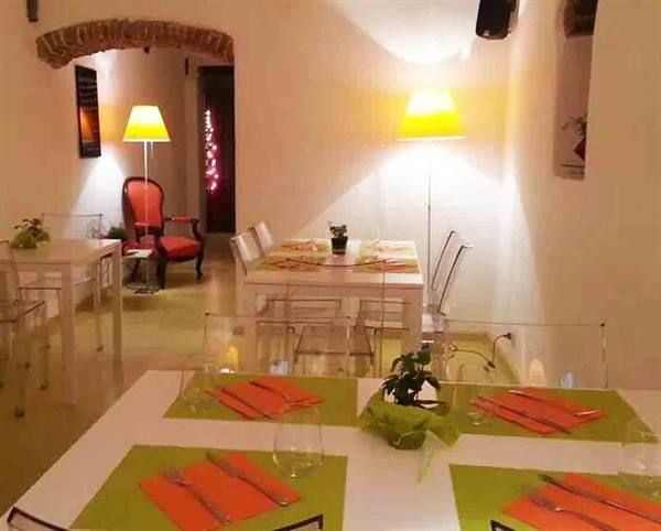 Restaurant dining room with set tables, green placemats, transparent chairs and yellow lamps