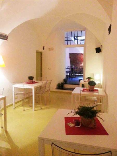 White vaulted dining room with tables, red placemats and transparent chairs