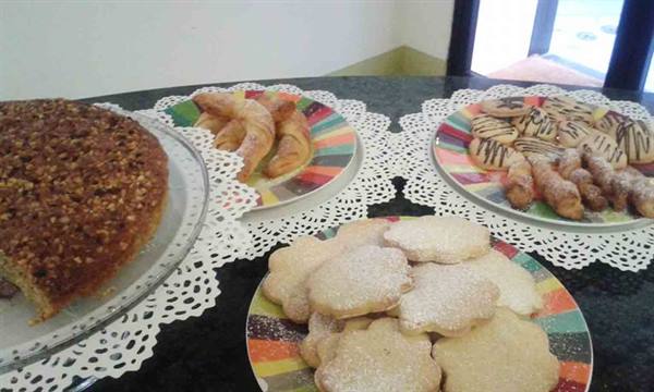 Nut cake, croissants and cookies on colorful plates with paper doilies