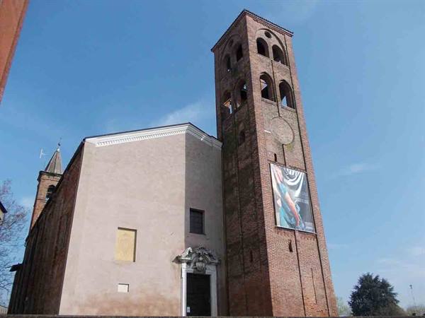 Brick church with Romanesque bell tower under blue sky