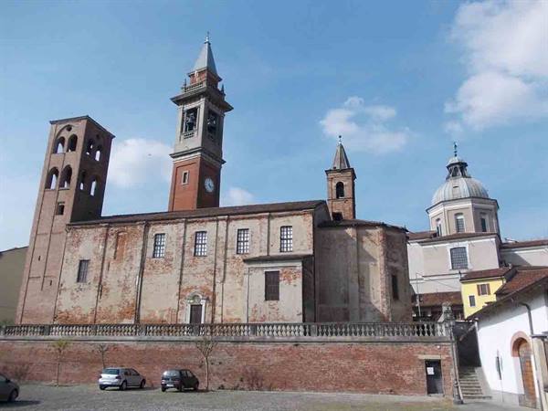 Brick church with bell tower and dome under blue sky, parked cars