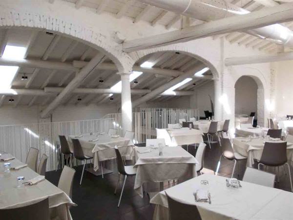 Whitewashed restaurant hall with brick vaults, wooden beams and set tables