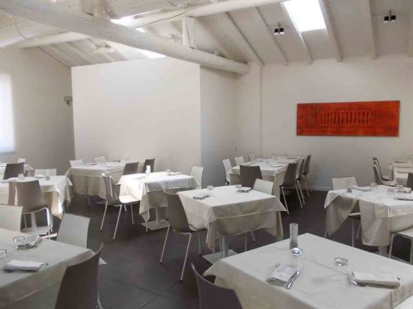 Restaurant dining room with white tablecloth tables and beamed ceiling