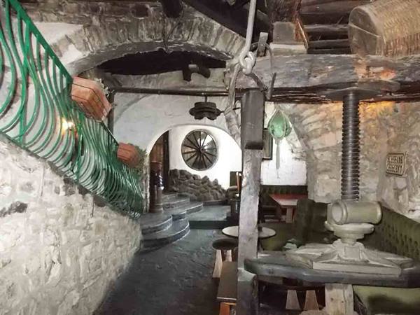 Stone interior with old screw press, wooden wheel and arched passages
