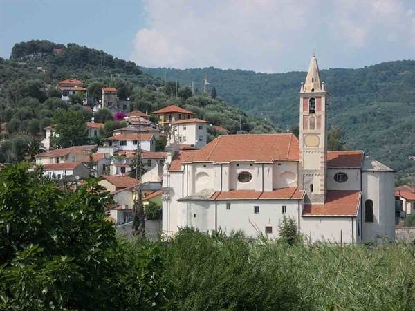 White church with pink bell tower and tiled roof among houses and hills