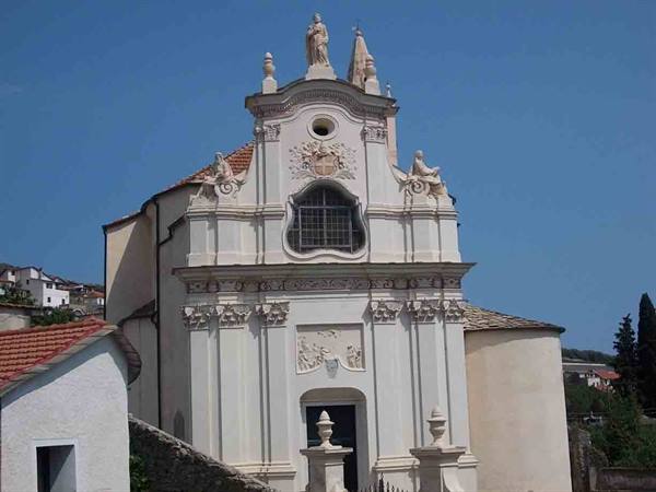 White baroque church with sculpted facade and statues under blue sky