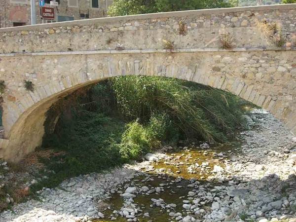 Stone arch bridge over a rocky stream with reeds