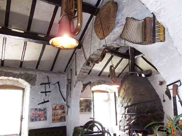 Horn and accordion hanging from wooden beams above a stone fireplace