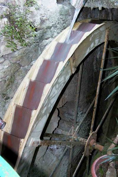 Hydraulic wheel of wood and metal with water flowing over the paddles