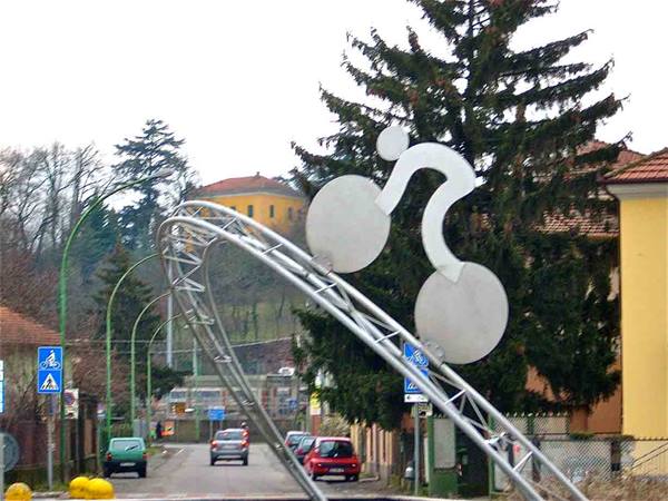 Metal cyclist sculpture over a road with cars and bike signs