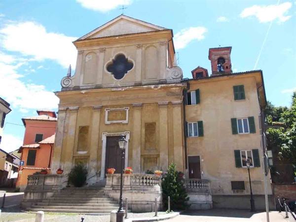 Ochre-yellow church with staircase, quatrefoil rose window and bell tower, blue sky