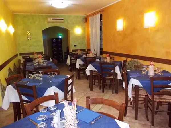 Trattoria dining room with set tables, blue tablecloths, wooden chairs and warm lights