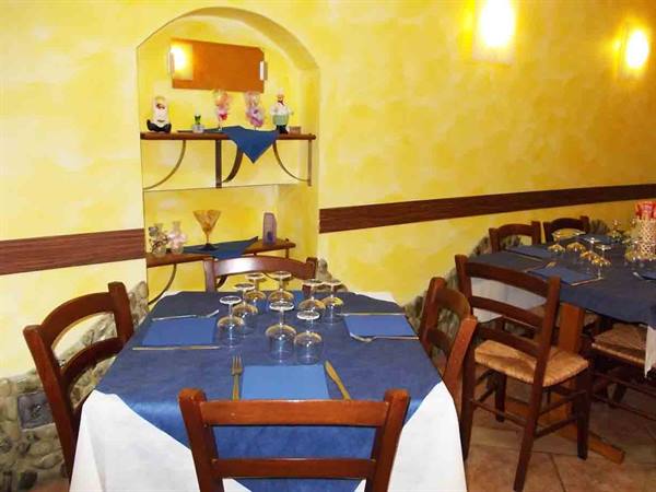 Tables set with blue tablecloths in a restaurant dining room with yellow walls