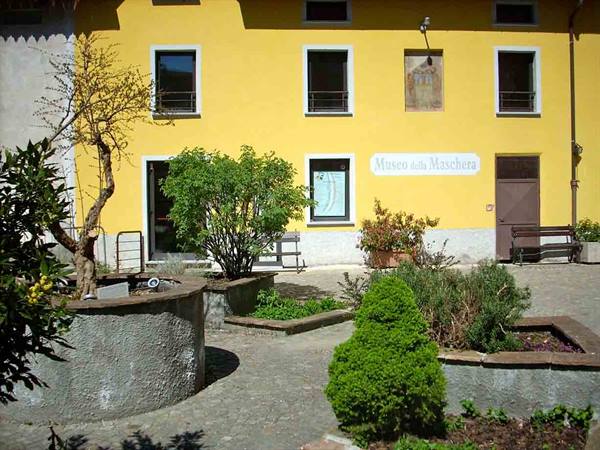 Yellow facade of the Mask Museum with stone planters and benches
