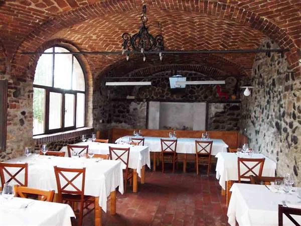 Trattoria dining room with brick vaults, stone walls and set tables