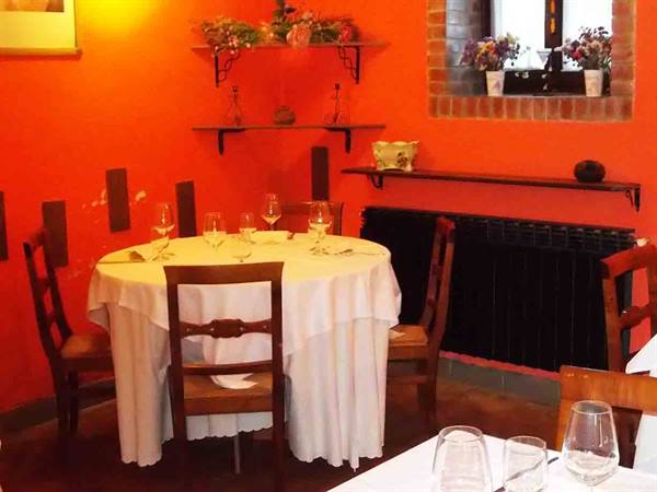 Set table with white tablecloth and wine glasses in orange-walled dining room