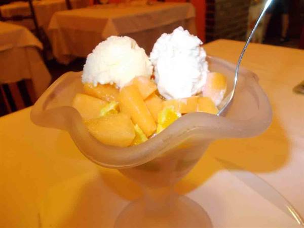 Frosted glass cup with ice cream and melon pieces, set table