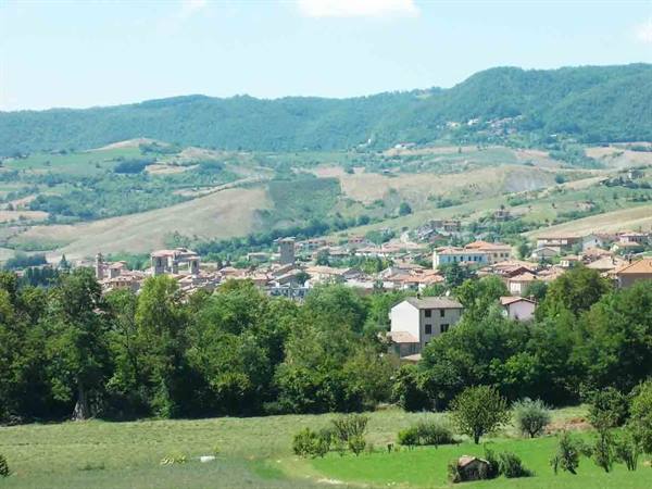 Small village with red rooftops among green wooded hills