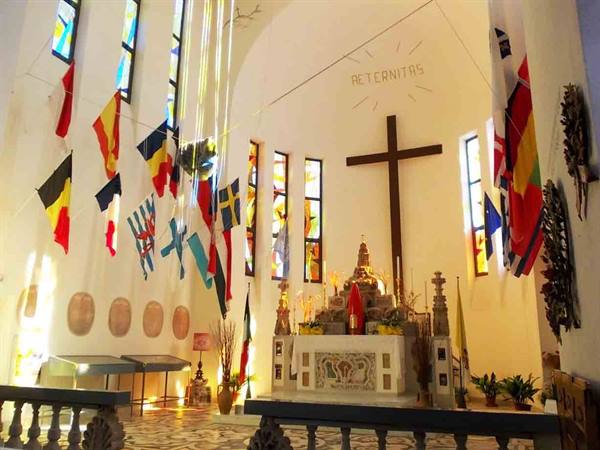 Church interior with altar, large wooden cross and international flags hanging