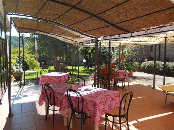 Tables with pink cloths under a cane pergola, iron chairs in the garden