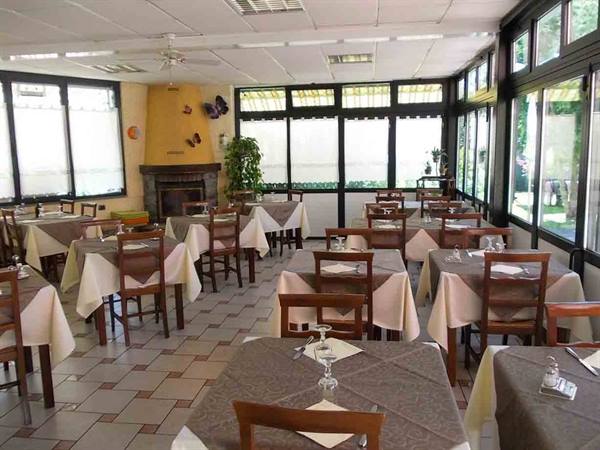 Empty restaurant dining room with set tables, white tablecloths, fireplace and large windows