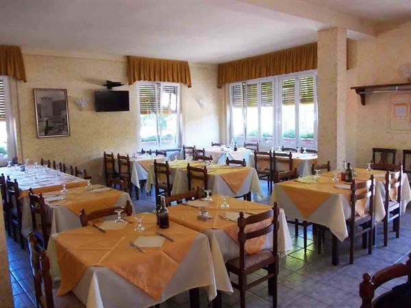 Restaurant dining room with set tables, white and orange cloths, light from windows