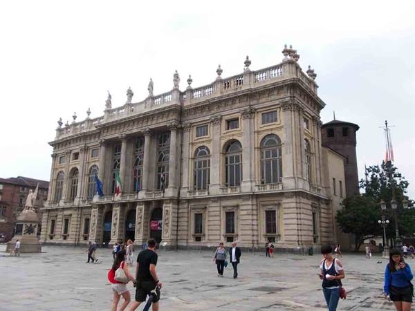 Tourists walk in front of Palazzo Madama in Piazza Castello, Turin